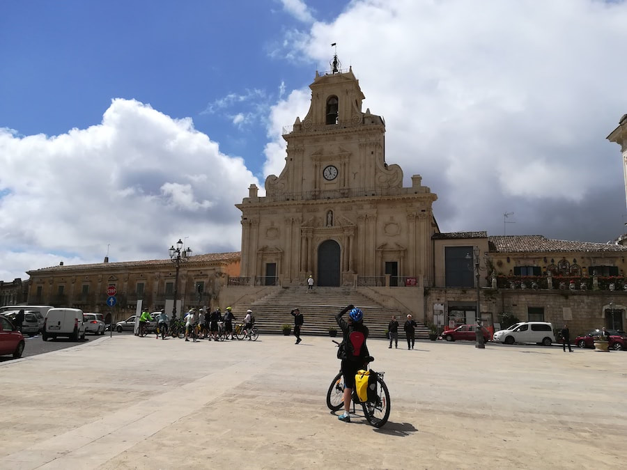 Cycliste devant une église baroque sur la place principale de Palazzolo Acreide